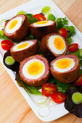 Traditional British picnic food - delicious Scotch eggs cut in halves with vegetable salad of greens and tomatoes..