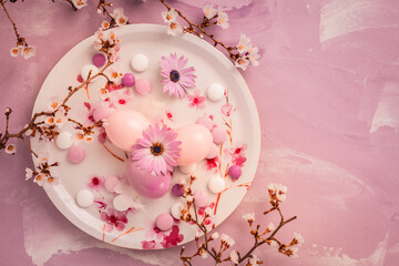 Pink Easter eggs with blooming branch and sweets for Easter and spring