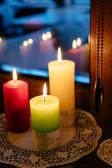 Colored candles are burning on a brown window sill. Romantic atmosphere for Valentine's Day.