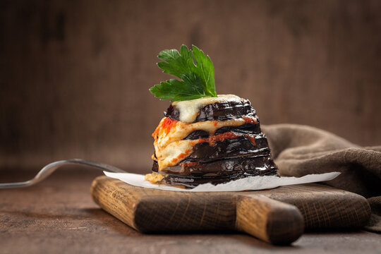 Parmigiana di melanzane - italian dish, deep fried eggplants baked with mozzarella, parmezan cheese and tomato sauce. Decorated with parsley.