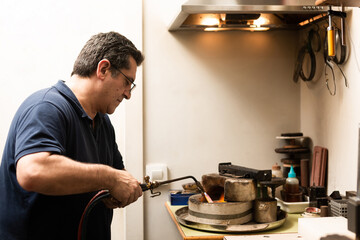 blowtorch melts silver in a jewelry workshop furnace