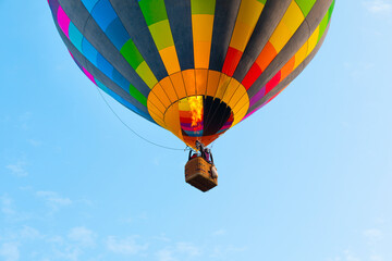 Bright colored beautiful hot air balloon fly on blue sky background of Pamukkale in Turkey, close-up. Fire will heat air in shell and rise higher.
