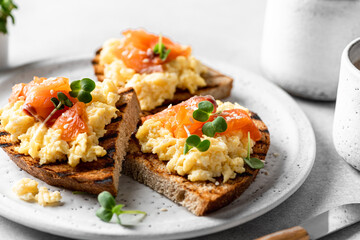 Scrambled egg sandwich with salmon on a ceramic plate on a white background, selective focus,...