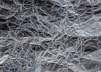 Wrinkled metal foil texture, silver color, grunge abstract background.