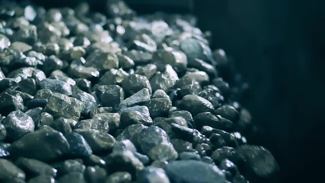 Pieces of copper ore are falling from the conveyor in slow motion