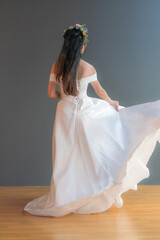 Backside image of standing bride wearing white wedding dress.