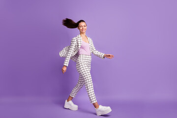 Full body profile side photo of charming happy pretty lady walk empty space fly hair isolated on violet color background