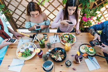 Young people taking food pictures with mobile smartphone to share on social media while having...