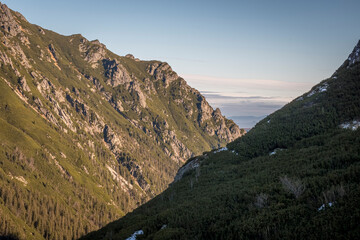 Slopes of Tatra Mountains leading into Valley of Roztoka, or Dolina Roztoki. One slope is illuminated by  morning sun while the other is in the shadow. Selective focus on the rocks, blurred background