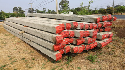 Pile of electric poles on the ground. New concrete poles overlaid on the side of the highway in...