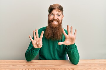 Young irish redhead man wearing casual clothes sitting on the table showing and pointing up with...