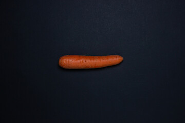 Carrots on a dark background. One carrot in the middle of the frame. Whole carrots on black background
