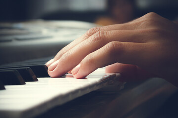 A woman plays the piano. Women's hands and keys close-up