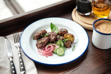 Mini beef cutlets with potato and cucumbers and a mug of coffee