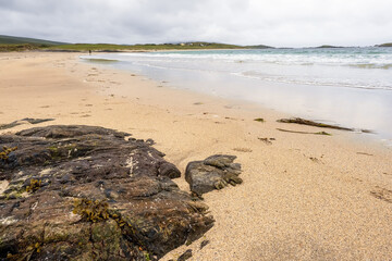 Big stone on a sandy beach in focus. Irish nature landscape, Atlantic ocean,West coast of Ireland. Cloudy sky.