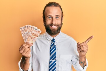 Handsome business man with beard and long hair holding 50 turkish lira banknotes smiling happy...