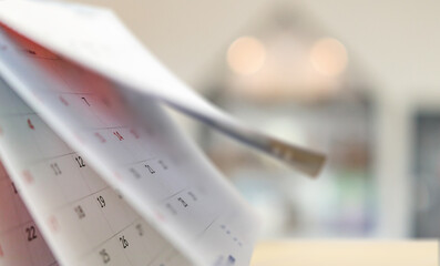 Close up white paper desk calendar with blurred bokeh background appointment and business meeting...