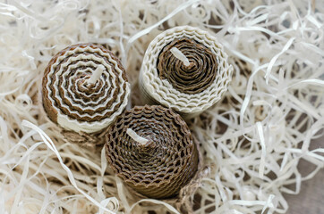 Obraz premium Wax honey candles in wood shavings. Decorations for the interior.