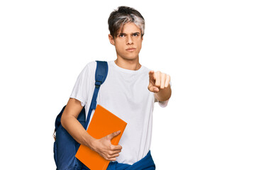 Young hispanic man wearing student backpack and holding books pointing with finger to the camera and to you, confident gesture looking serious
