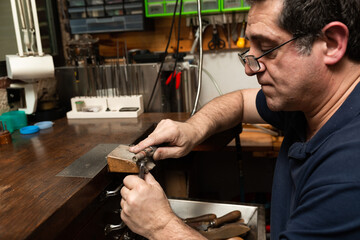 goldsmith sands a silver ring on the workbench.