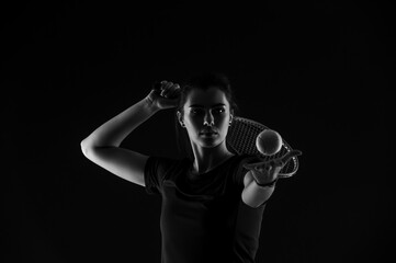 Tennis girl with racket serve ball on dark background. Player doing sport workout online. Sport and recreation concept. Black and white color filter