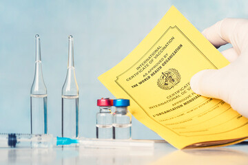 the International Certificate of vaccination, syringe and ampoules are on the table in the lab....