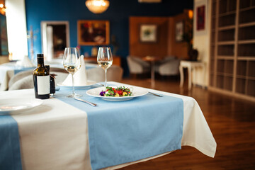 Gourmet peeled tomatoes salad on the table with a glass of white wine