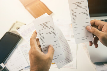 The young man was looking at the bill to calculate his income and expenses. In his hand there were bills to pay a lot in debt.