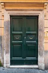 Old dark green wooden door in retro style in Italian residential building.