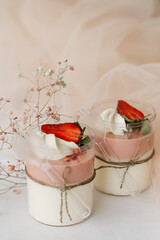 sweet desserts in a glass decorated with fresh strawberries and cream on the table