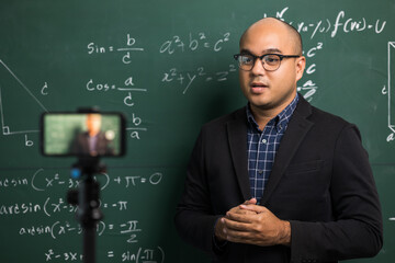 Indian young teacher man teaching online video conference live stream by smartphone. Asian teacher teaching mathematics class webinar online for students learning.