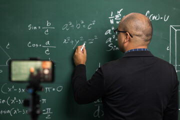 Indian young teacher man teaching online video conference live stream by smartphone. Asian teacher teaching mathematics class webinar online for students learning.