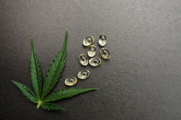 Medicinal cannabis leaves with cbd oil. Marijuana oil in medical capsules isolated on black background.