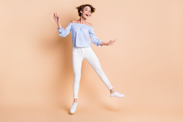 Fototapeta na wymiar Full body photo of young excited girl happy positive smile have fun dream jump up isolated over beige color background