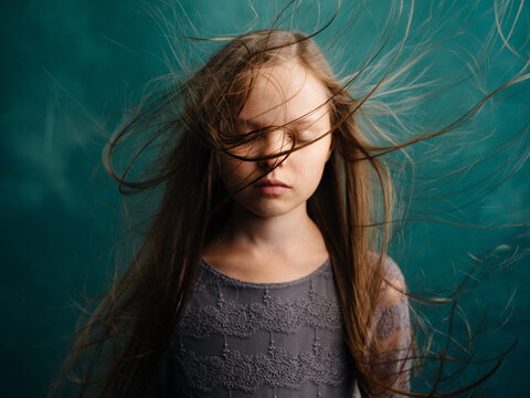 Portrait of a beautiful girl with closed eyes on a turquoise background and loose hair