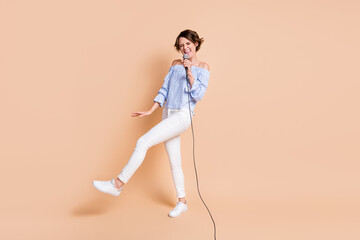 Fototapeta na wymiar Full size photo of young crazy excited girl happy smile enjoy performance sing microphone karaoke isolated over beige color background