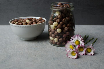 Fototapeta na wymiar Chocolate balls, Healthy breakfast Breakfast cereal background. Beautiful food decoration with violet flowers. The texture of the cereal. Copy space.