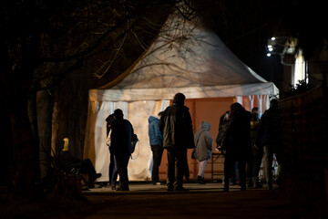 People stand in long queues on cold night in front of the checkpoint as they wait to receive the...
