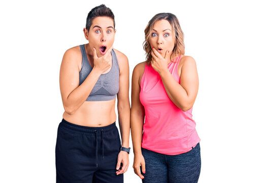 Couple of women wearing sportswear looking fascinated with disbelief, surprise and amazed expression with hands on chin