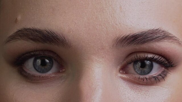 A young woman opens her eyes and looks into the camera. Extreme close-up.