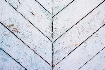 old boards with old peeling paint of gray-blue color are laid out with a herringbone pattern