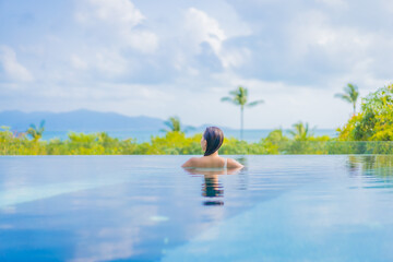 Fototapeta na wymiar Portrait beautiful young asian woman enjoy around outdoor swimming pool with sea view