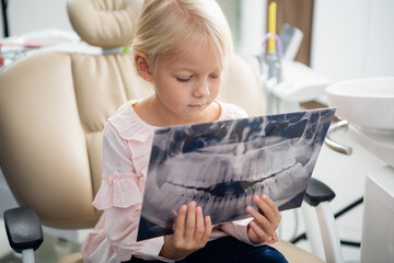 Close up of a cute little female child examining an x-ray of a j