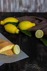 Homemade lemon cookies. Black wooden background with lemons and leaves.