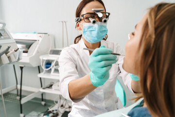 European dentist woman using microscope while working in dental clinic - obrazy, fototapety, plakaty