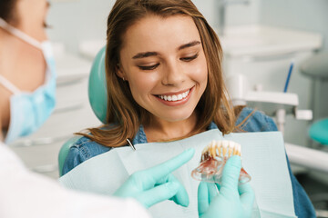 Dentist woman showing teeth imitation to her smiling patient