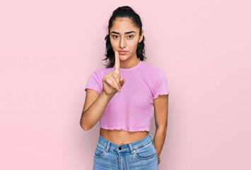 Hispanic teenager girl with dental braces wearing casual clothes pointing with finger up and angry expression, showing no gesture