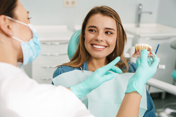 Dentist woman showing teeth imitation to her smiling patient