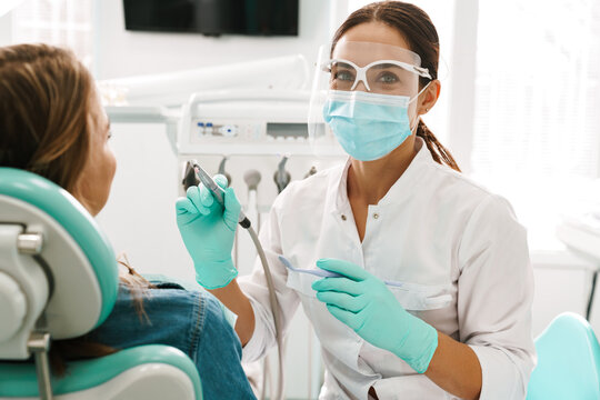 European mid dentist woman in face mask working in dental clinic