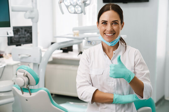 European mid dentist woman showing thumb up in dental clinic